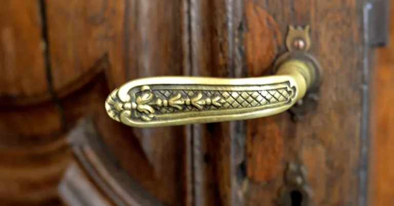Antique brass lever door handle mounted on a carved wooden door