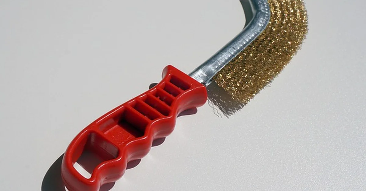 Wire brush with red handle used to remove paint and rust from wood surfaces