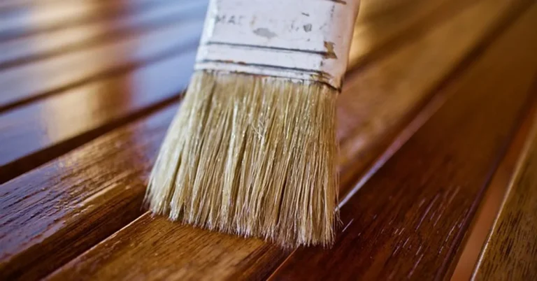 Brush applying satin wood finish to a wood surface
