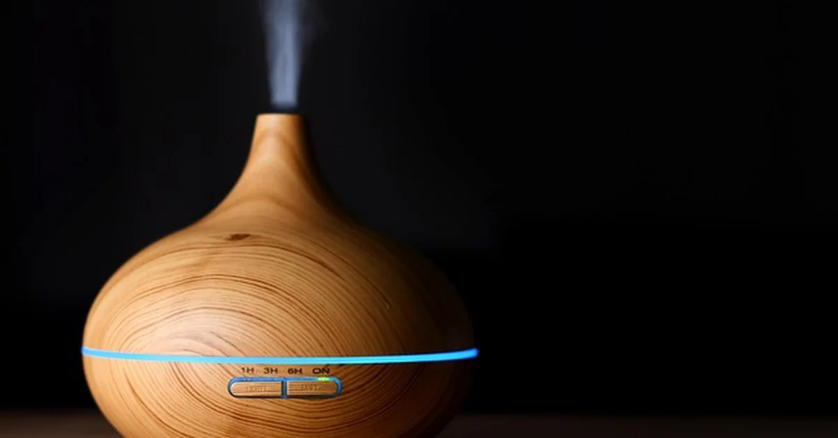 Wood-grain essential oil diffuser releasing mist on a wooden table