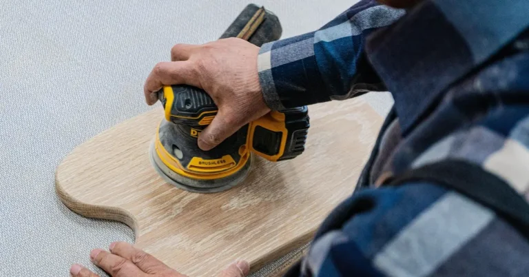 Detail sander tool being used on a wood workpiece edge