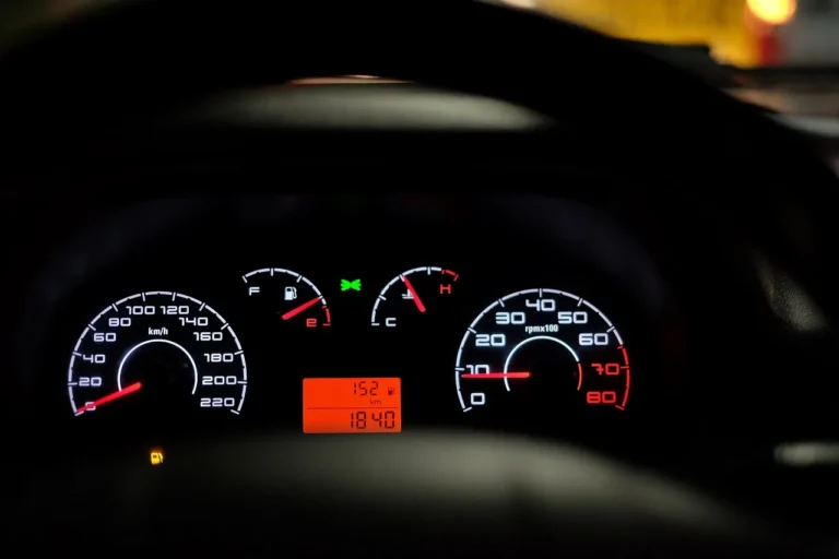 Illuminated car dashboard at night showing speedometer, tachometer, fuel and temp gauges, and a digital display reading 152