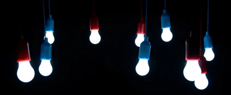 Several glowing light bulbs hang from cords against a black background
