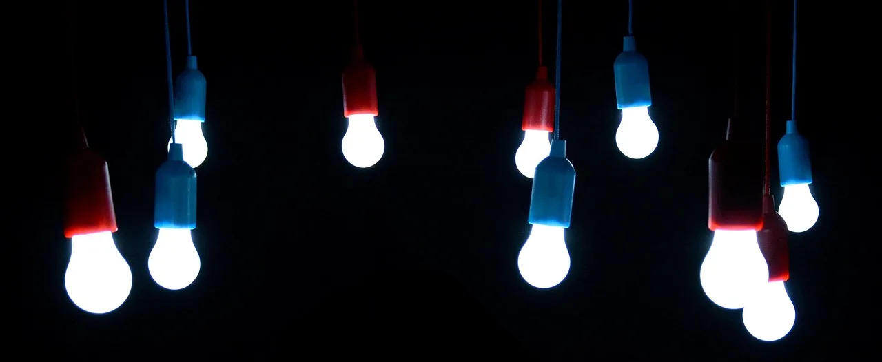Several glowing light bulbs hang from cords against a black background