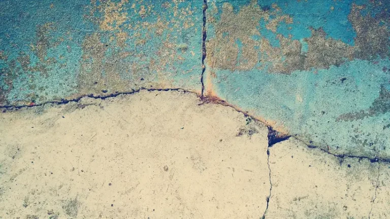 Homeowner and contractor inspecting a concrete driveway crack with tools beside the joint