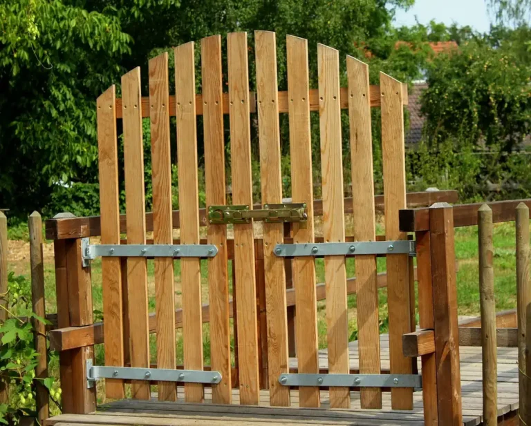 Wood fence gate with galvanized hinges and latch being checked for sag in natural light