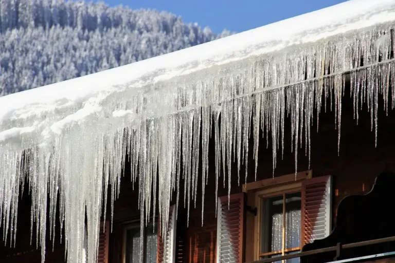 Gutter edge on a snowy house roof with ice buildup and a homeowner inspecting winter damage