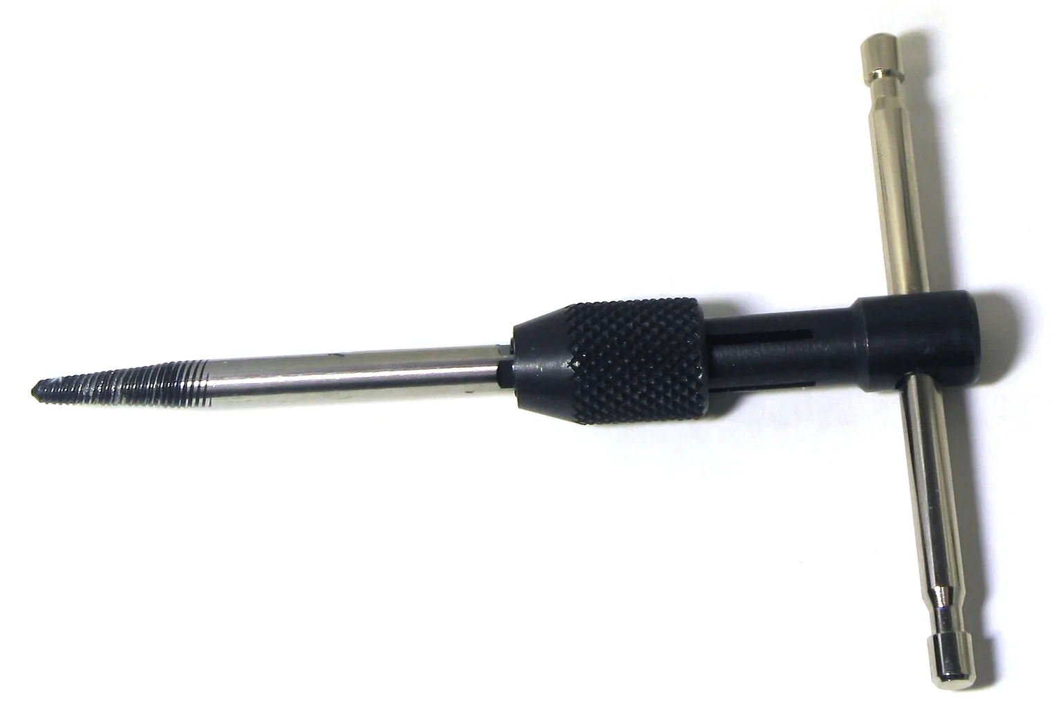 Close-up of a left-hand drill bit starting to remove a stripped screw in a clamped metal part