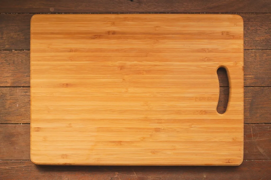 Hand oiling a wooden cutting board with visible grain and knife marks
