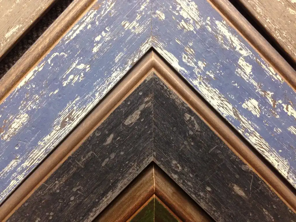 Close-up of a picture frame corner being sanded and finished, showing grain and joint detail