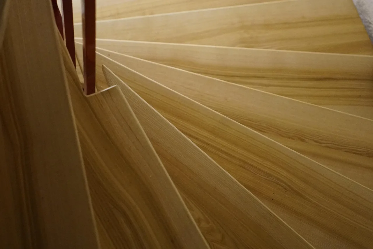 Homeowner and designer compare wood stair tread samples beside a modern staircase
