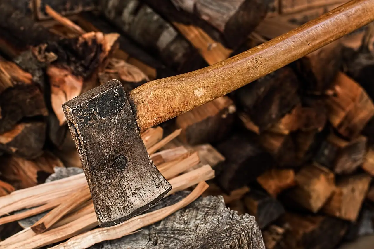 Split firewood stacked beside a wood stove in a cozy room with natural window light