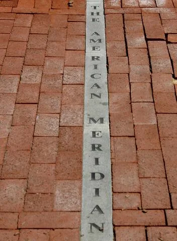 Hand measuring a brick wall opening with mortar joints and laid bricks visible