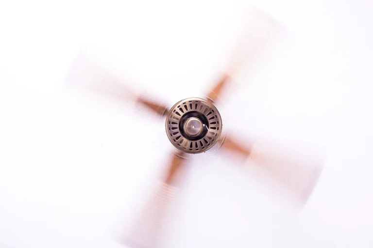A ceiling fan with DC motor above a living room sofa while a person adjusts the controls.