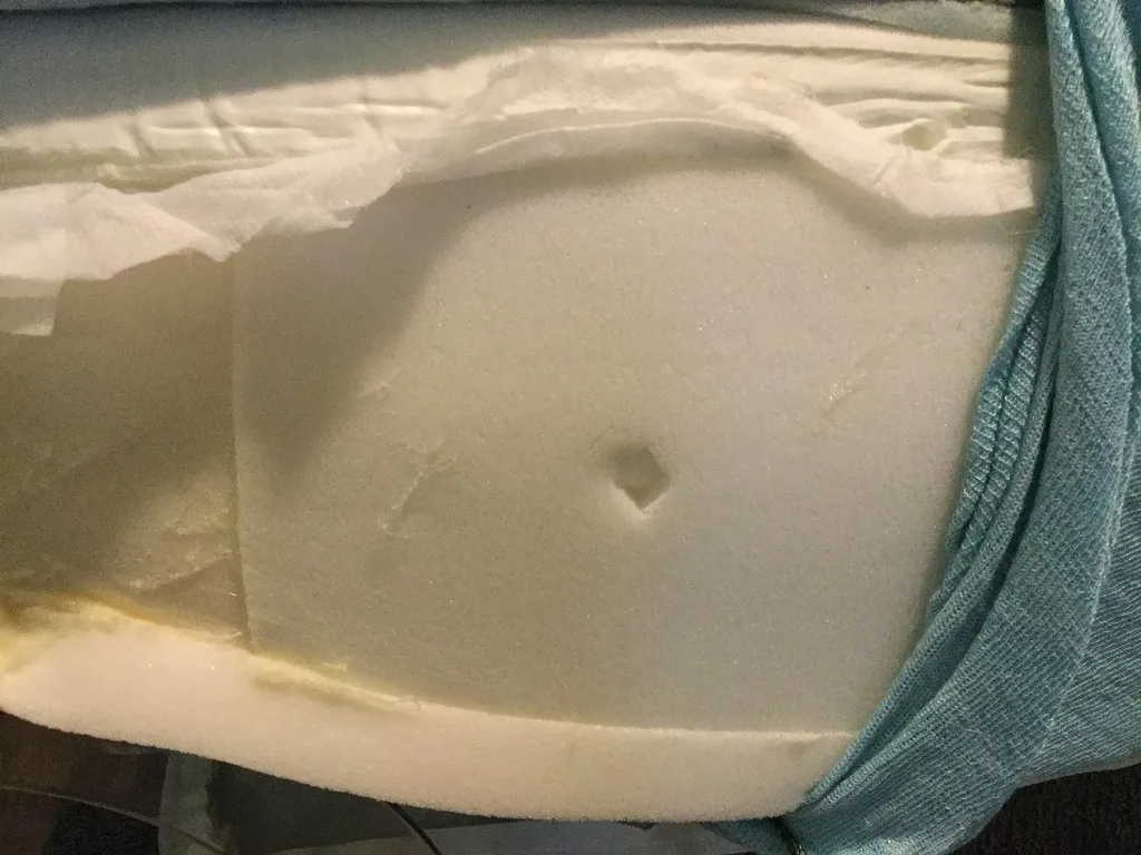 Close-up of a side sleeper checking lower-back space and support on a mattress.