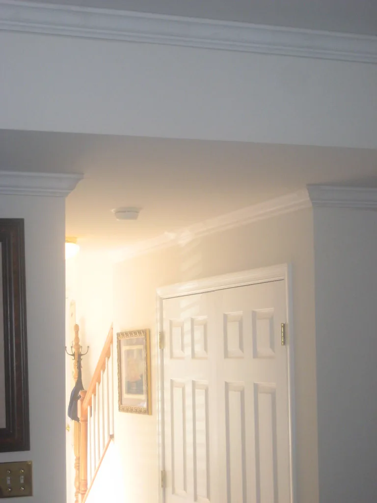 Hands comparing a crown molding profile with angle tools beside a miter saw