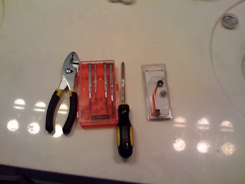 Worn faucet cartridge and rubber washer held in gloved hands over a towel