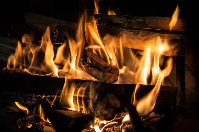 Homeowner checking a fireplace and nearby smoke detector in a bright living room