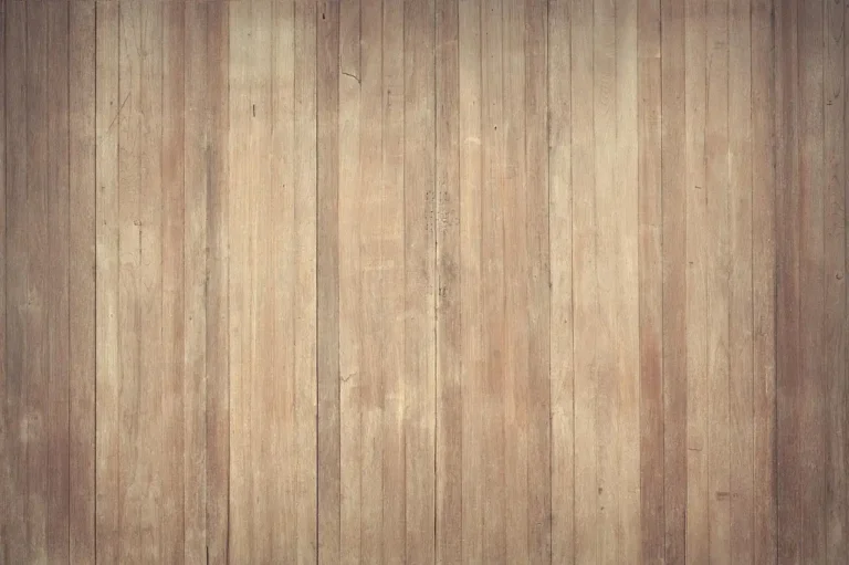 A person dry mopping a sunlit hardwood floor in a living room
