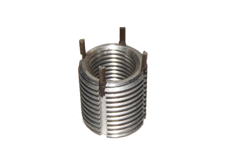 Mechanic comparing a wire coil insert and a solid thread repair insert beside damaged metal threads