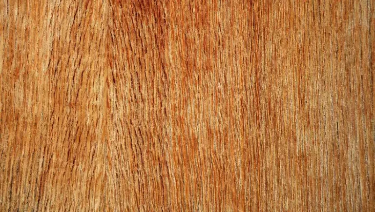 Close-up of a reddish-brown wood surface showing vertical grain patterns and natural texture