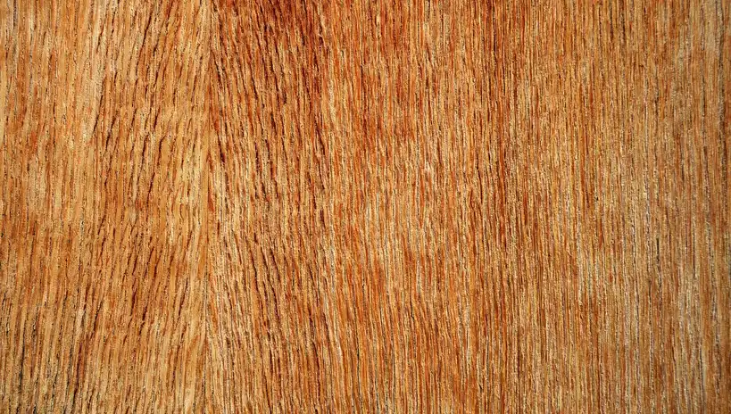 Close-up of a reddish-brown wood surface showing vertical grain patterns and natural texture