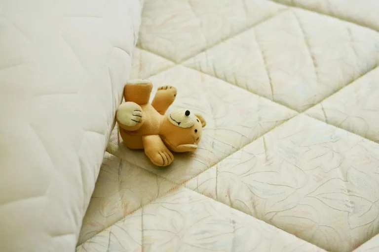 Person checking a mattress indentation and bed frame support in a sunlit bedroom