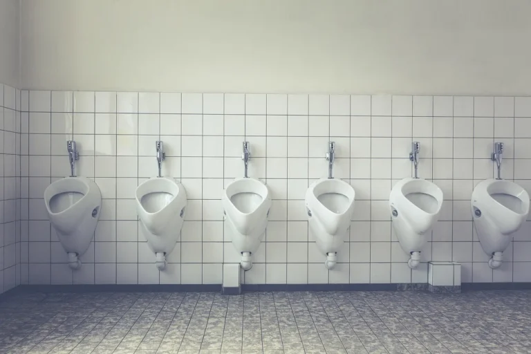 Row of white urinals on a tiled restroom wall