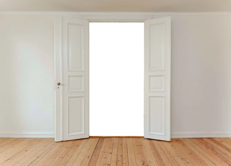 Open white double doors in a bare room with wooden floor