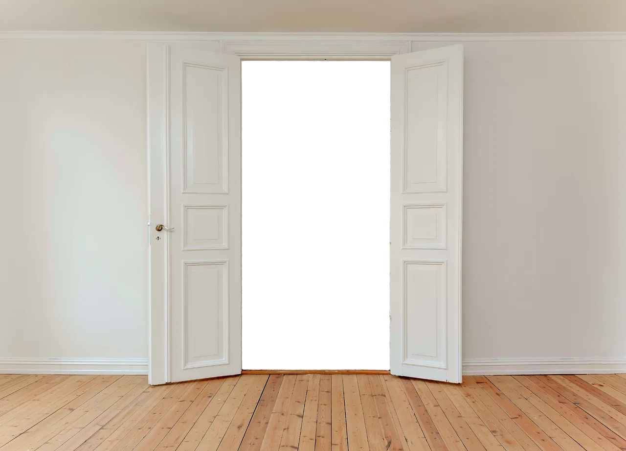 Open white double doors in a bare room with wooden floor