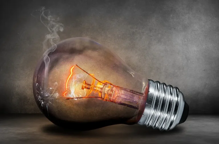 Homeowner comparing LED, CFL, and incandescent bulbs on a kitchen table near a dimmer switch