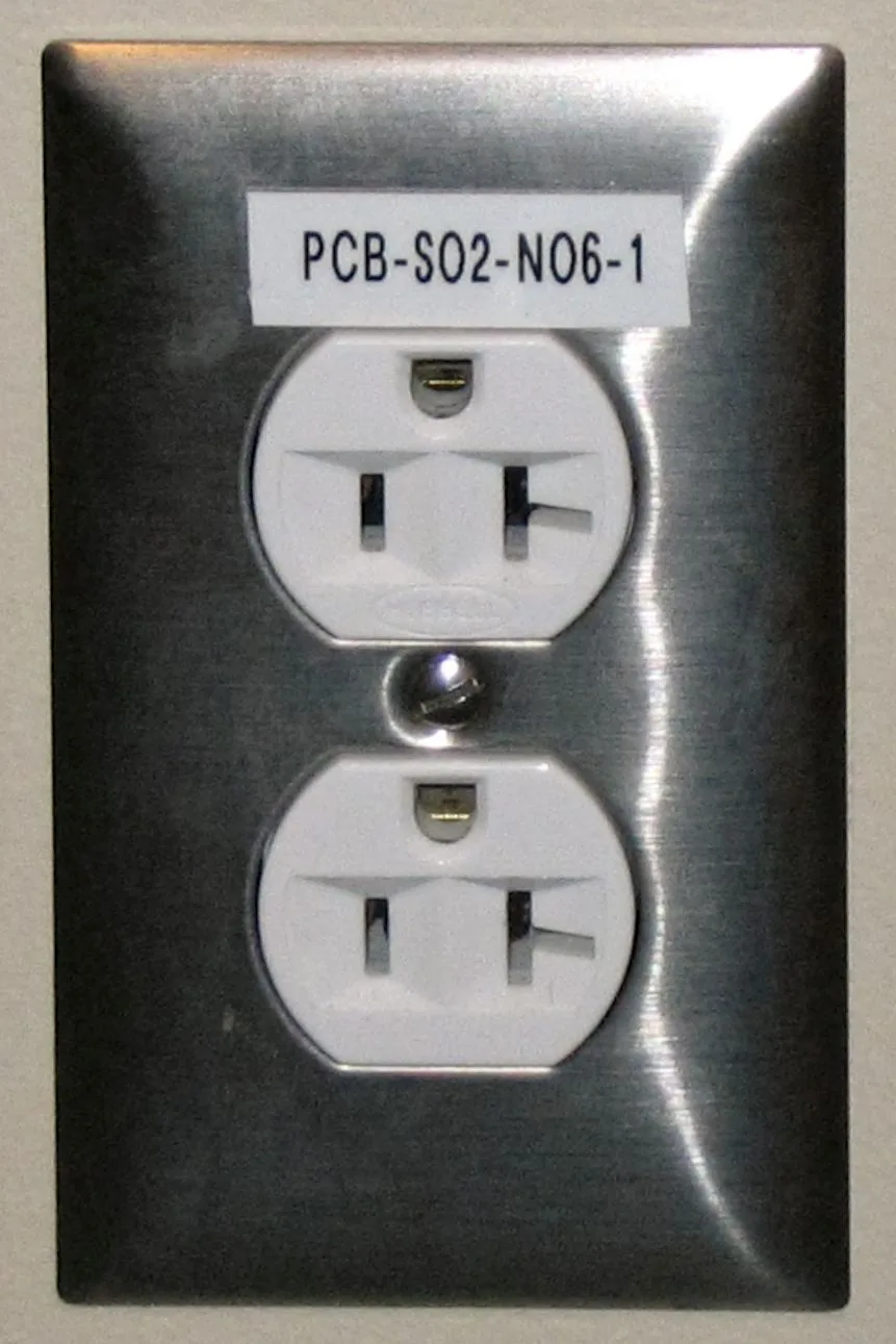 Close-up of a receptacle with backstab and side-wire connections in an open outlet box