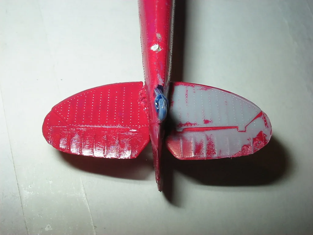 Gloved hand testing paint removal on a wooden surface with a plastic scraper
