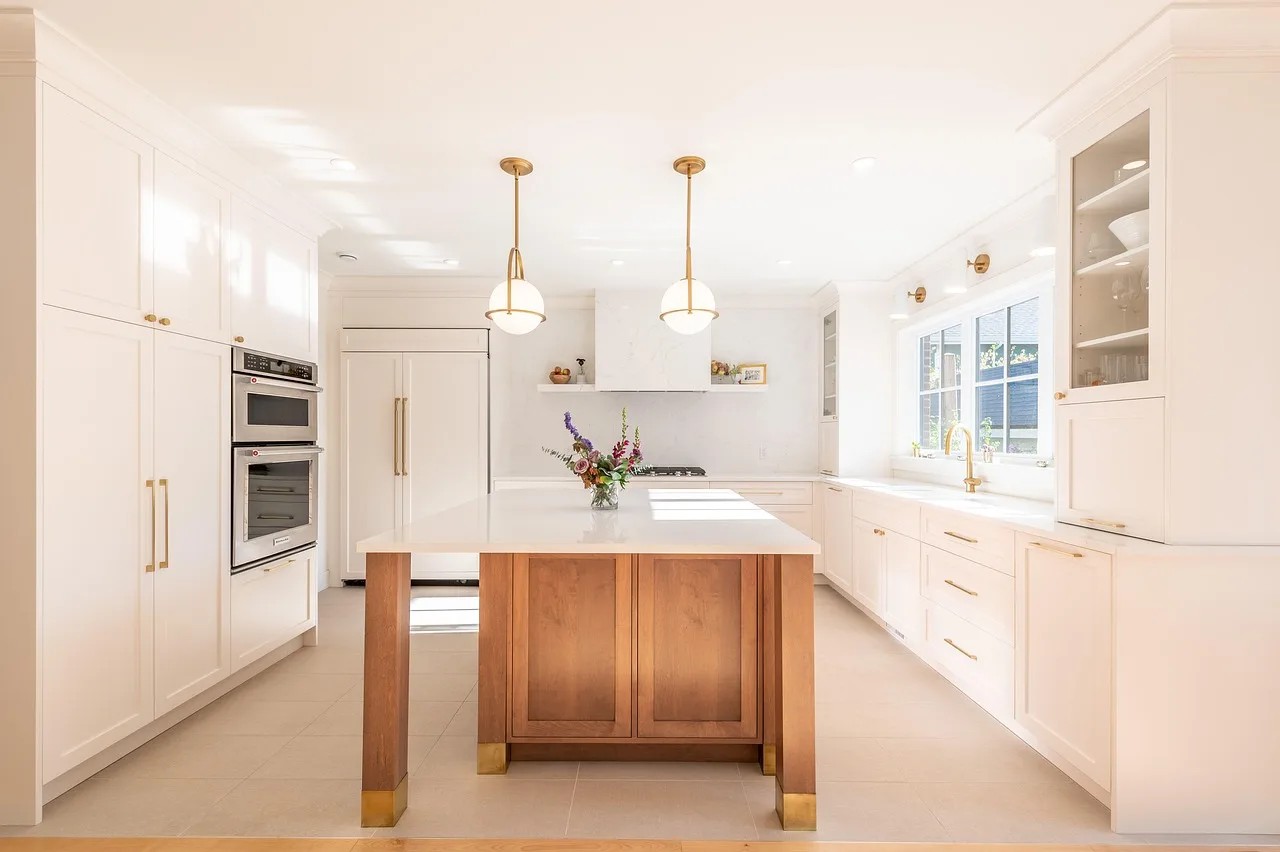 Person wiping a wood kitchen cabinet with a microfiber cloth in natural light.