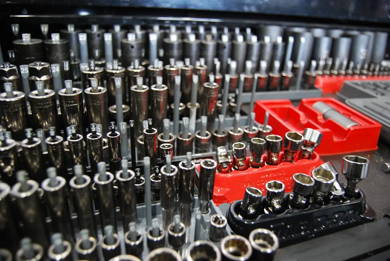 Ratchet tools and sockets on a mechanic’s bench beside a car engine