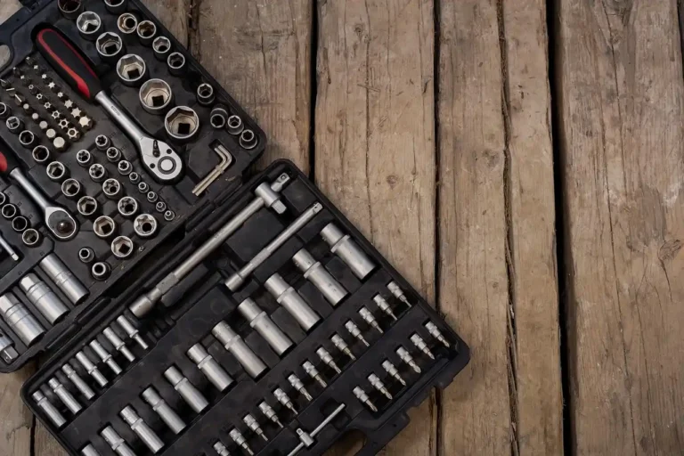Mechanic compares a ratchet wrench and socket wrench in a garage beside an engine bay