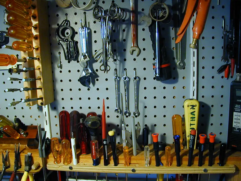 Close-up of a loose hinge and screws on a sagging kitchen cabinet door
