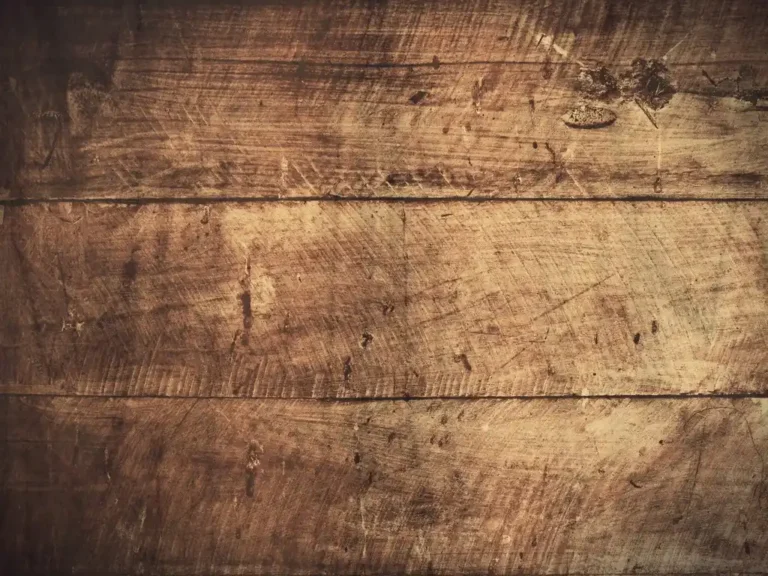 Close-up of three horizontal, weathered wooden planks with visible grain, scratches, and dark knots