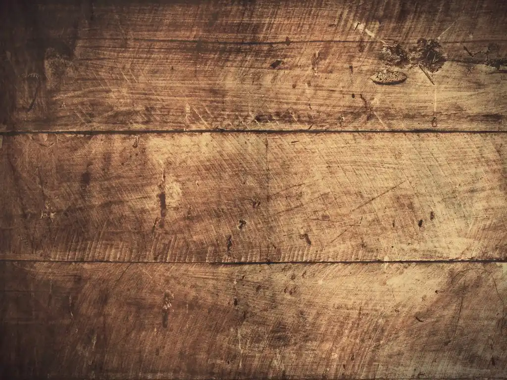 Close-up of three horizontal, weathered wooden planks with visible grain, scratches, and dark knots