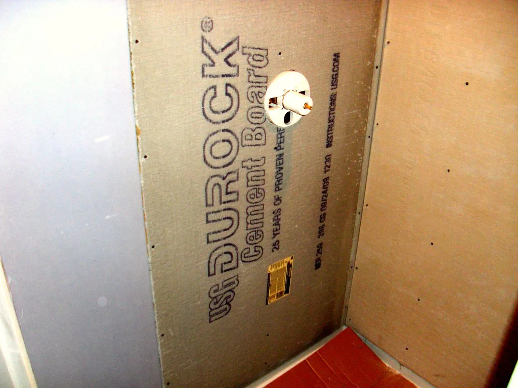 Tile installer and homeowner inspecting a subfloor with a straightedge and moisture meter