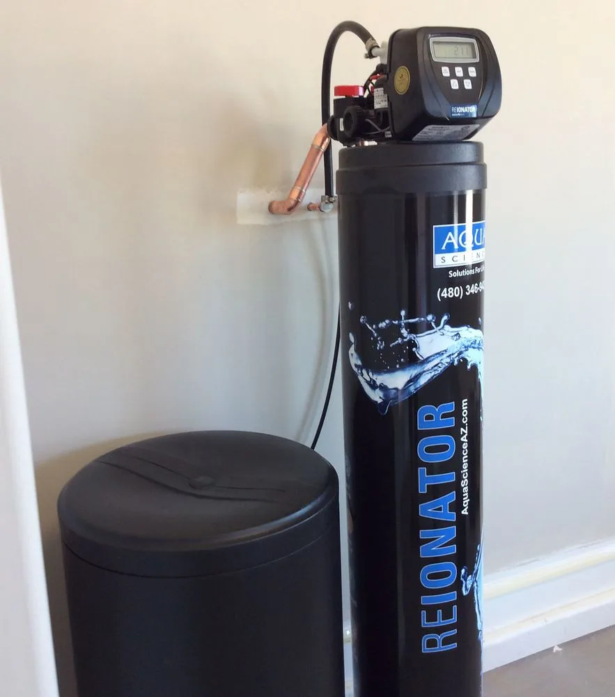 Close-up of a reverse osmosis under-sink filter and a glass of clear drinking water.