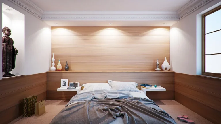 A calm bedroom with a bedside lamp casting warm light beside a person reading in bed.