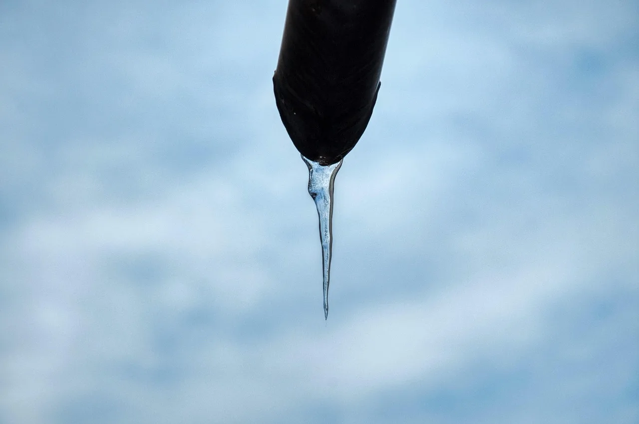 Homeowner checking frozen pipes under a kitchen sink on a winter morning