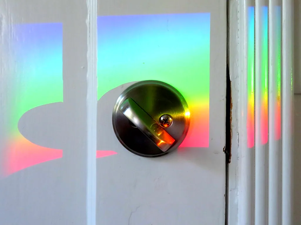 Close-up of a deadbolt latch engaging a strike plate in a wooden door frame.