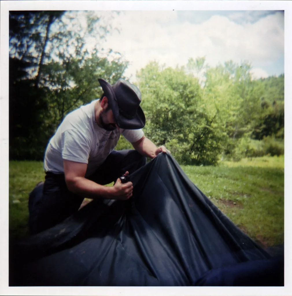 Person kneeling beside an air mattress, checking seams in a sunlit bedroom