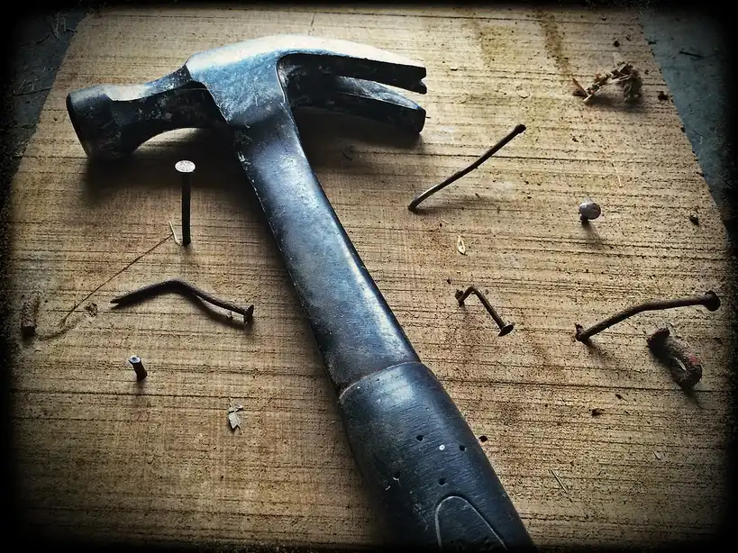 Homeowner inspects a scratched wooden table with repair tools on a sunlit workbench